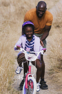 Young man pushing his daughter on her bike